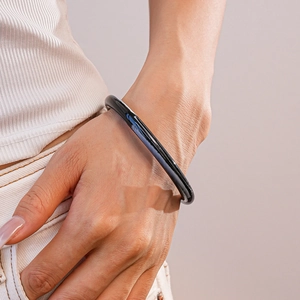 Détail d'un bracelet jonc noir en acrylique poli sur le poignet avec une finition brillante