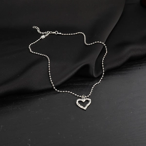 Detailed view of silver irregular heart pendant on a bead chain necklace over black silk