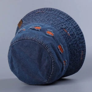Detail of distressed blue denim bucket hat with vibrant orange hole texture and stitching