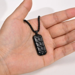 Macro detail of black stainless steel rectangle pendant with textured chevron tire pattern
