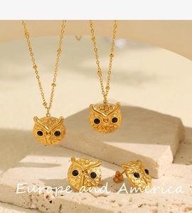Detailed view of gold owl jewelry set with black zircon eyes on stone plate