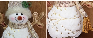 Detail showing plush snowman doll with gold branch pattern and fabric hat on wood