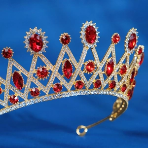 Macro view of gold bridal crown with red gemstones and white rhinestones on blue fabric