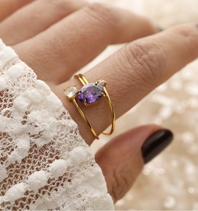 Nahaufnahme eines doppellagigen Goldrings mit ovalem violettem Stein am Finger