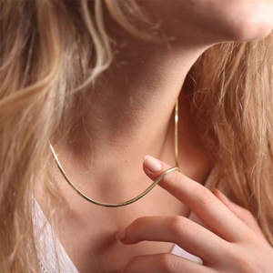 Close-up detail of a minimalist gold-plated stainless steel snake chain necklace for women.