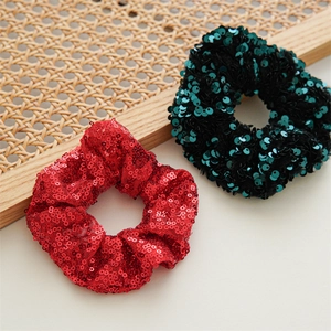Close-up of red and dark green sequined elastic scrunchies on a natural tray