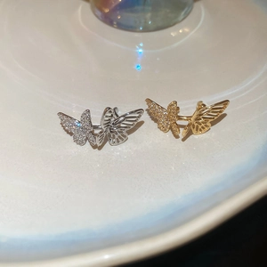 Macro view of gold and silver butterfly ear cuffs with sparkling zircon and hollow design