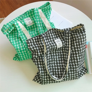 Detail of green and grey canvas tote bags with polka dot patterns and woven handles