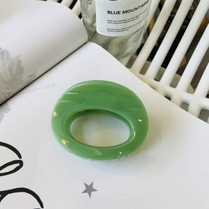 Macro detail of glossy grass green oval hair claw clip with a thick resin butterfly hinge