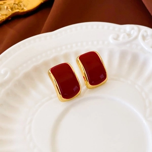 Macro detail of wine red enamel rectangular studs with gold borders on ceramic