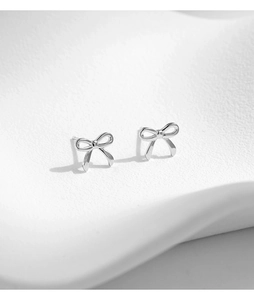 Macro shot of minimalist s925 silver bow stud earrings with polished metallic finish