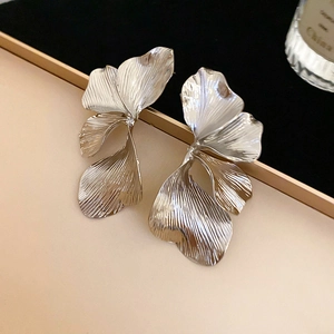 Dettaglio di orecchini a fiore in argento con petali testurizzati e finitura metallica rétro