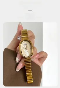 Macro detail of golden oval watch with mother of pearl dial and metal link bracelet