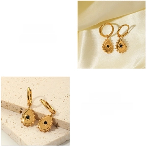 Detail of vintage teardrop gold earrings with black stones on a silk fabric background