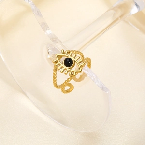 Detail of gold evil eye ring with black bead on a glass edge over silk fabric