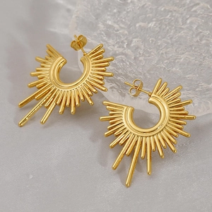 Macro shot of gold sunburst earrings featuring radiant metal texture and polished finish