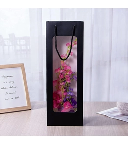 Detail of black paper gift bag with transparent window and black handle on a wood table