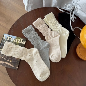Dettaglio di cinque calze in cotone con trama a coste su un tavolo in legno scuro