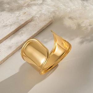 Close-up of a wide polished 18K gold-plated wave cuff bracelet with minimalist curves