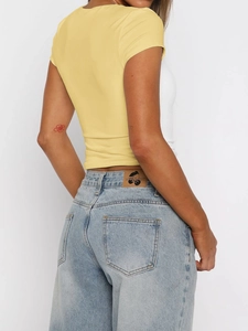 Back view of a yellow slim fit cropped t-shirt paired with light blue denim jeans