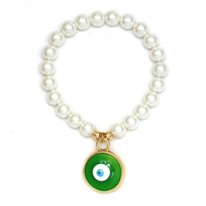 Makroaufnahme eines Armbands mit weißen Perlen, grünem Evil Eye Anhänger und Goldakzenten
