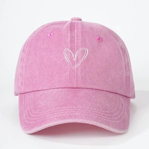 Detailed view of the heart-shaped embroidery on a pink washed cotton kids baseball cap