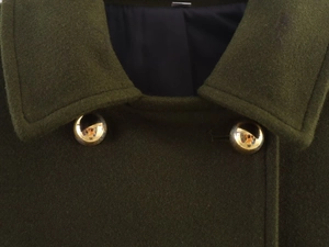 Detail of dark green wool coat showing thick texture and golden hemispherical buttons
