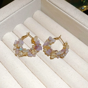 Close-up of golden wire-wrapped earrings with irregular pastel crystals and pearls