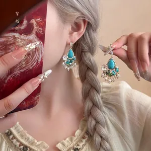 Dettaglio di orecchini vintage in turchese con perle bianche e accenti in oro