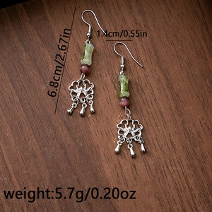 Macro detail of Chinese style long tassel earrings with beads and silver flower pendant