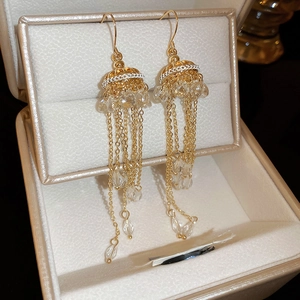 Close-up of gold tassel earrings with artificial crystals on a luxury jewelry box