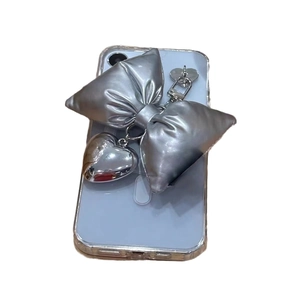 Silver bow heart keychain pendant on blue phone showing metallic puff heart detail