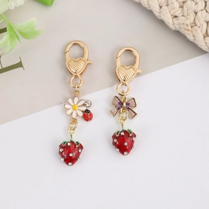 Detail of strawberry keychains with enamel ladybug, daisy flower and crystal bow charms