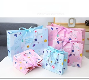 Detail of starry sky gift bags with pink and blue planet patterns and ribbon bows