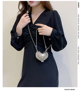 Detail of silver heart-shaped metal bag with radial texture and chic bead chain strap
