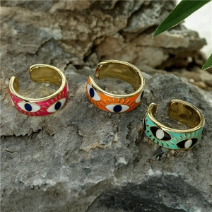 Detailed close-up of three colorful enamel evil eye rings on natural rock background