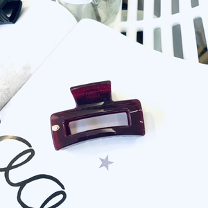 Macro shot of rectangular dark red resin hair claw clip on white starry background
