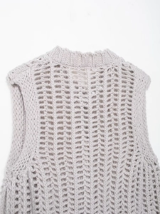 Dettaglio del gilet in maglia grigio chiaro con scollo a coste e motivo a trama traforata