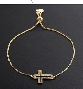 Detail of adjustable gold box chain bracelet with sparkling zircon pave cross pendant