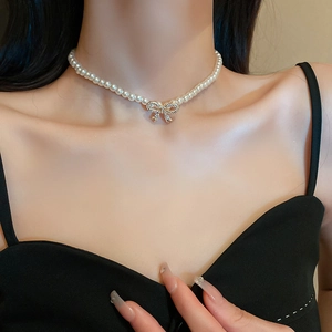Close-up of pearl necklace with rhinestone bow pendant worn on neck