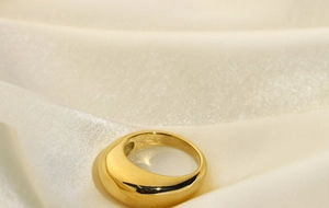 Gros plan d'une bague dorée bombée sur de la soie blanche avec éclat métallique
