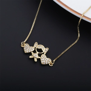 Detail of a gold box chain necklace with a girl pendant and sparkling heart-shaped zircon