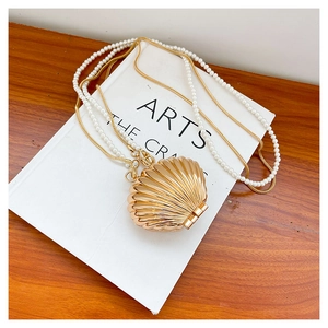 Detail of golden shell evening bag featuring pearl and metal chain straps
