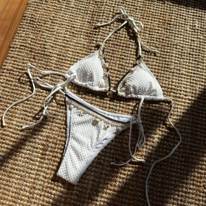 Detailed texture of white crochet bikini with gold-accented seashell and starfish charms