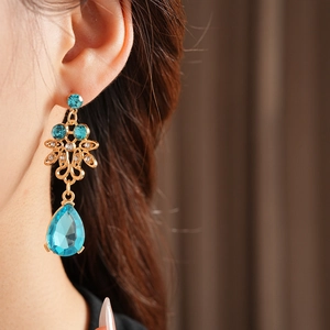 Detail of vintage flower pendant earrings with blue teardrop gemstone and small diamonds
