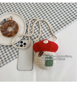 Detail view of handmade crochet mushroom crossbody bag next to a smartphone for scale