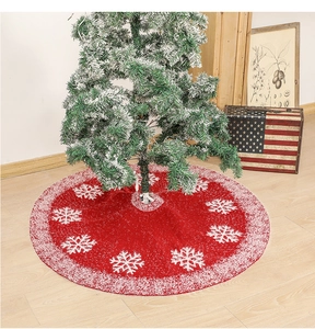 Detail of red knitted Christmas tree skirt with white snowflake patterns and plush trim