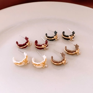 Close-up of matte C-shaped bow earrings with gold wire wrap and crystal accents