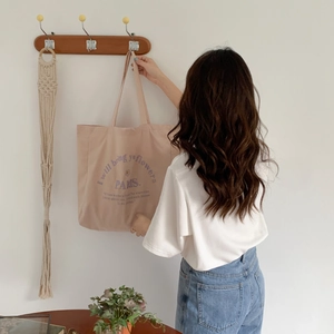 Detail of minimalist beige canvas tote bag with purple Paris floral embroidery on hook