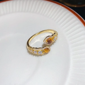 Macro detail of a gold snake-style open ring with tiger eye stones and white zircons